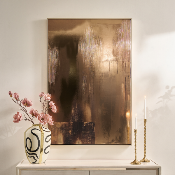 Vertical abstract canvas wall art featuring metallic gold and warm bronze tones, mounted above a console table with tall candlesticks.