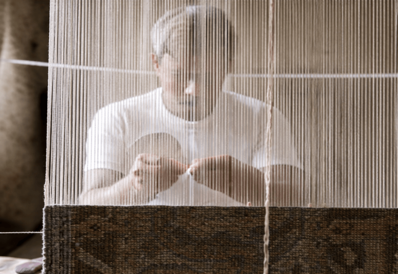 Close-up of an artisan hand-spinning raw natural wool yarn using traditional spinning tools.