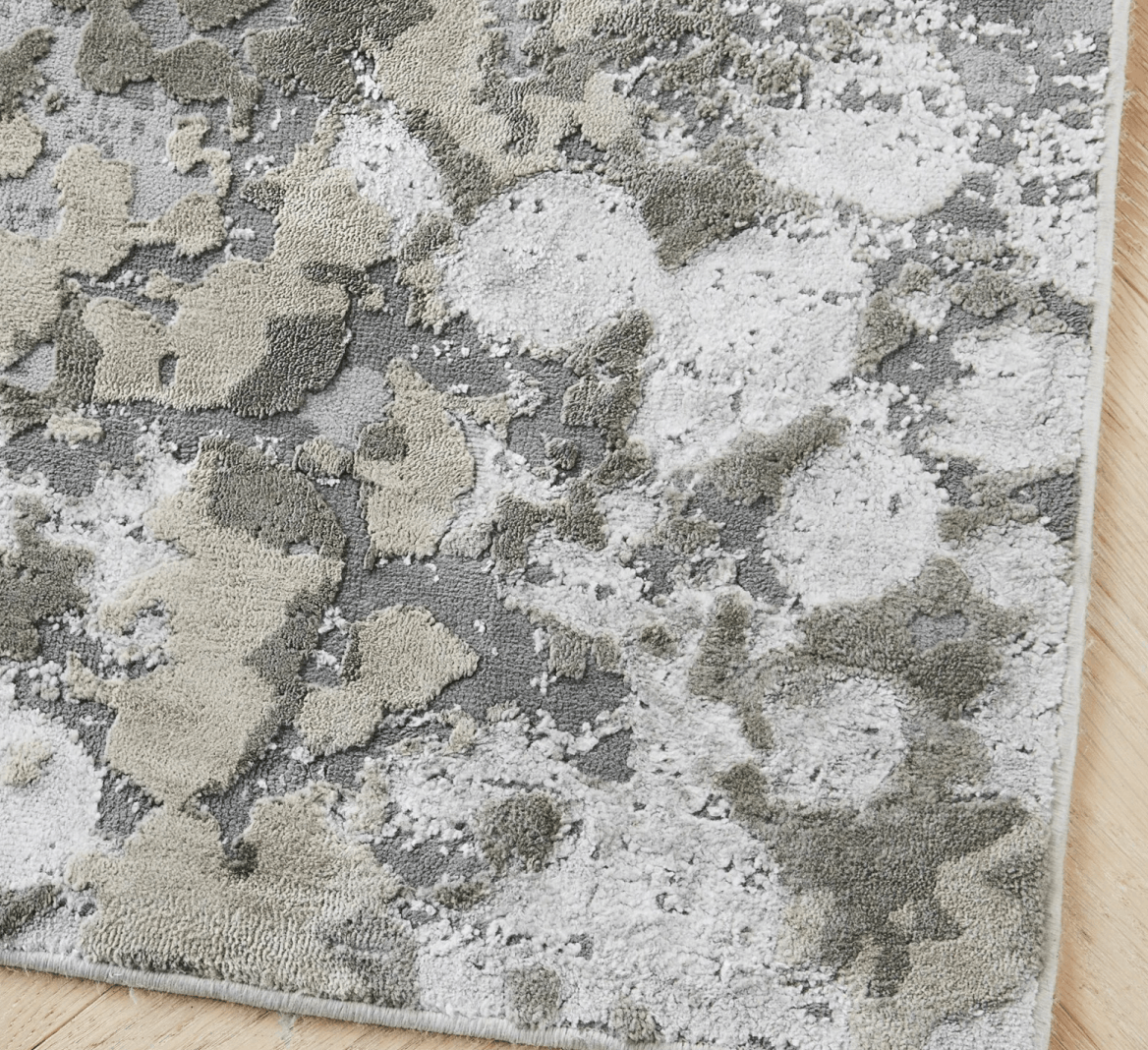 Detailed texture of a distressed abstract performance rug in silver, grey, and cream durable fibers.