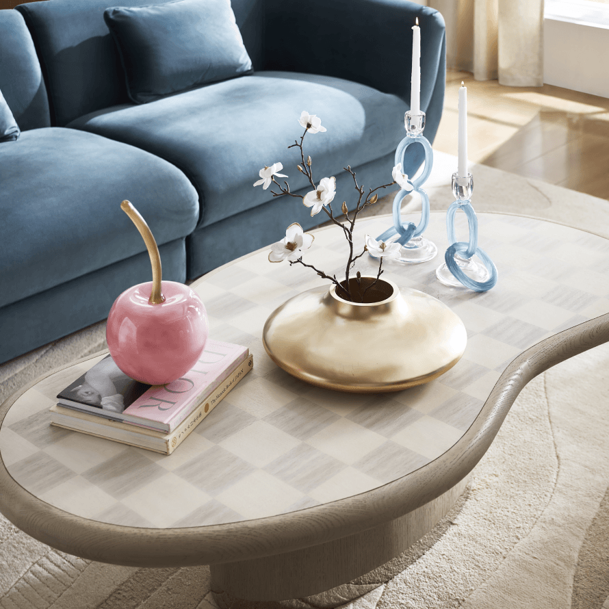 Modern living room styling with a blue velvet sofa and an organic curved coffee table with brass decor.