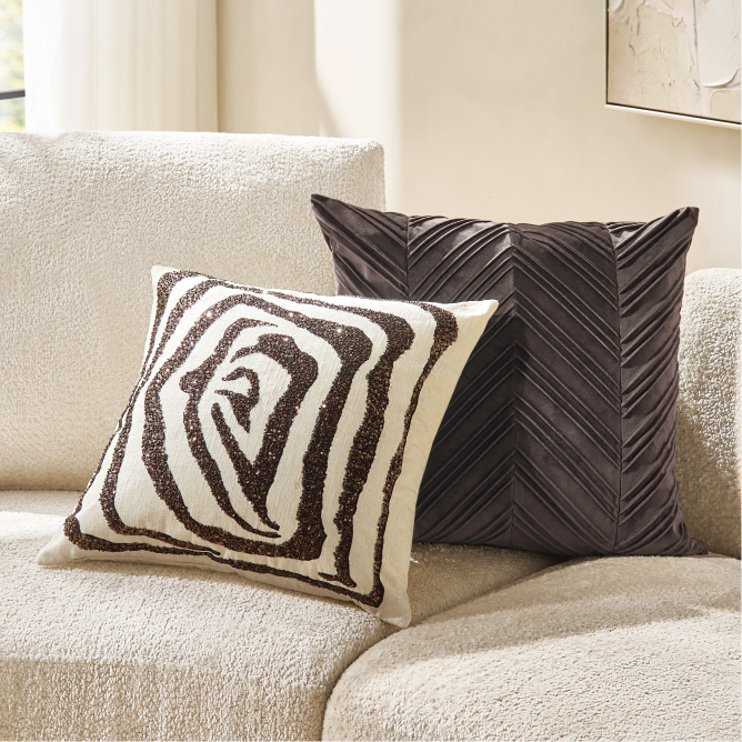 Cream boucle sofa styled with a black and white zebra pattern embroidered pillow and a dark pleated velvet throw pillow.