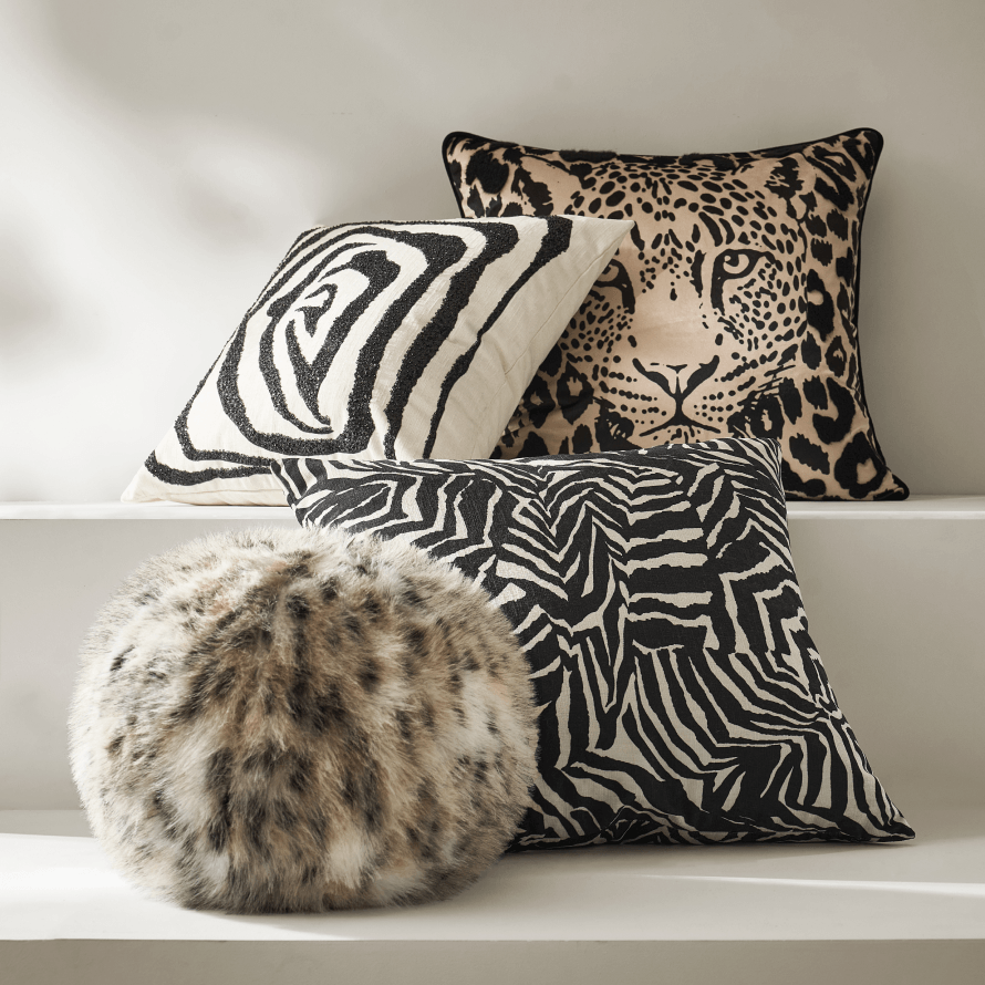 Assortment of luxury accent pillows featuring leopard print, zebra stripe, and fluffy faux-fur round pillow.