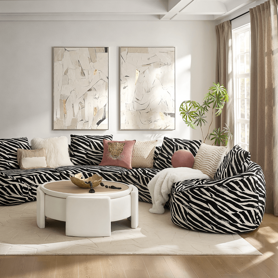 Living room with zebra pattern curved sectional sofa, white ottoman coffee table, and framed abstract art.