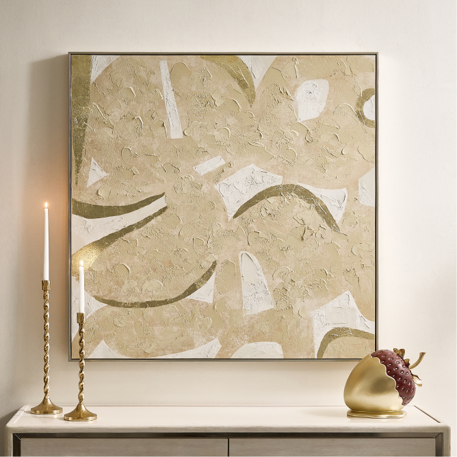 Large square abstract wall art featuring textured cream, gold, and neutral brushstrokes above a console table with tall brass candle holders.