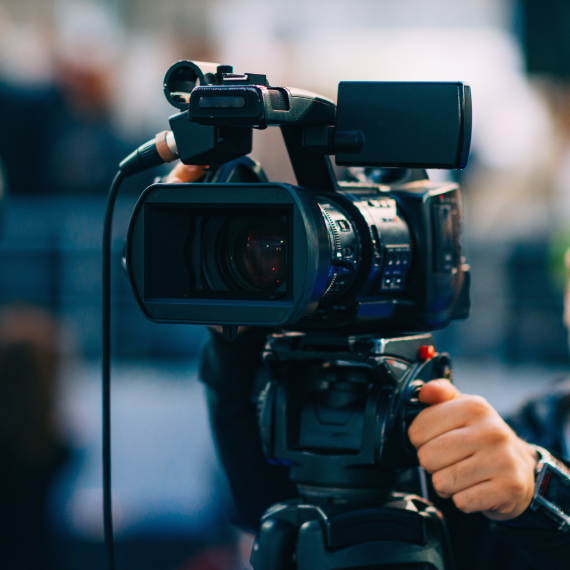 Professional video camera mounted on a tripod being operated in a studio environment. title: Read Z Gallerie press coverage, news, and media features