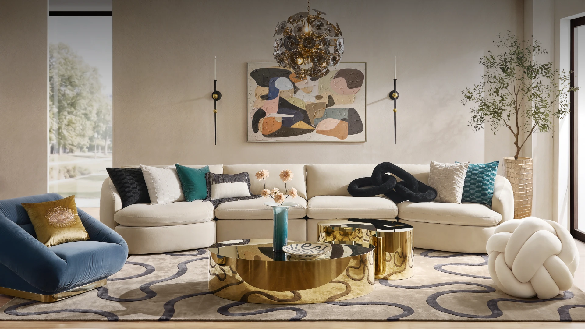 Contemporary modern living room featuring a curved cream sectional sofa, round brass coffee table, blue accent chair, and abstract wall art.
