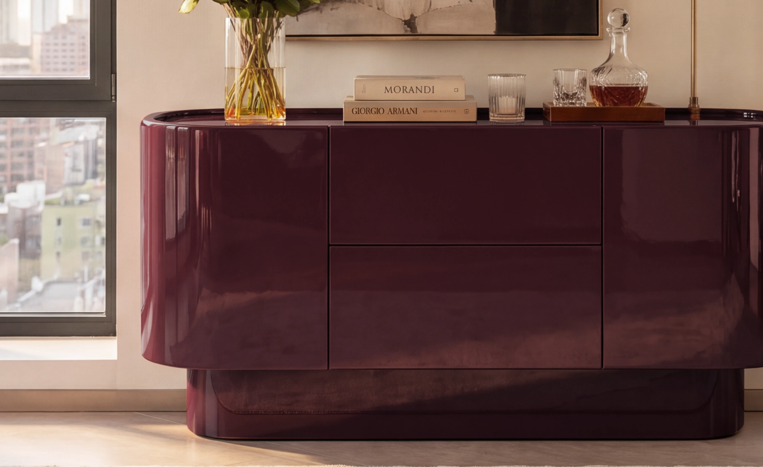 Velar Lacquered Buffet in high-gloss plum with curved edges, styled with coffee table books, floral vase, and decanter in a city apartment.