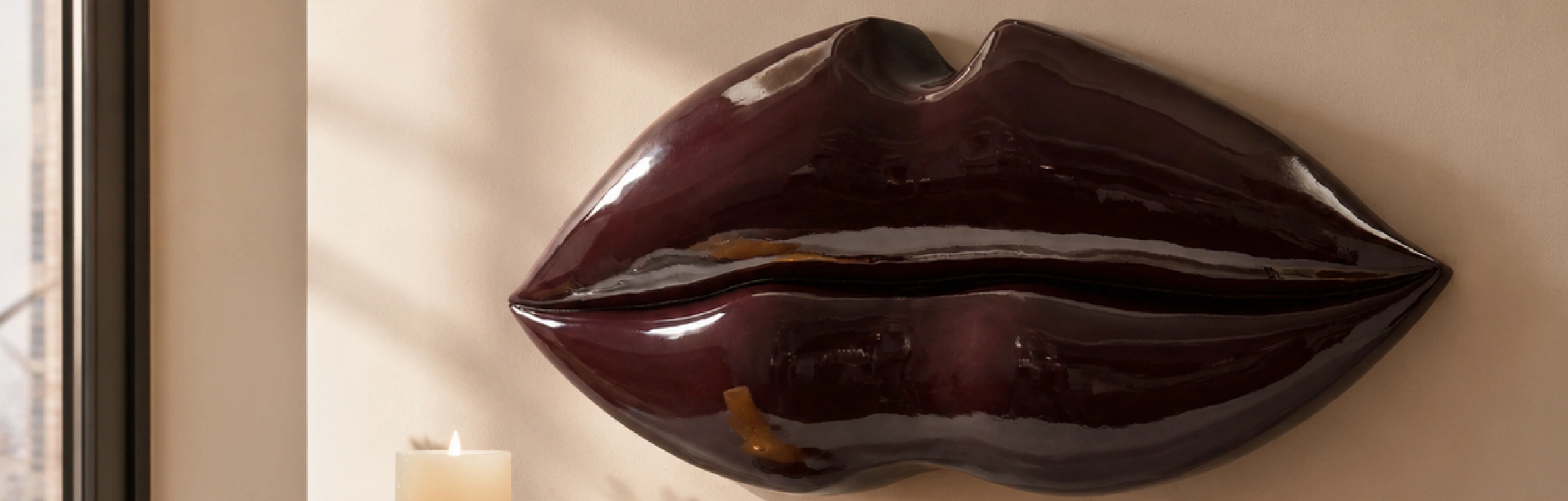 Grand Lips Wall Decor in glossy deep burgundy lacquer mounted on a neutral wall next to a window.
