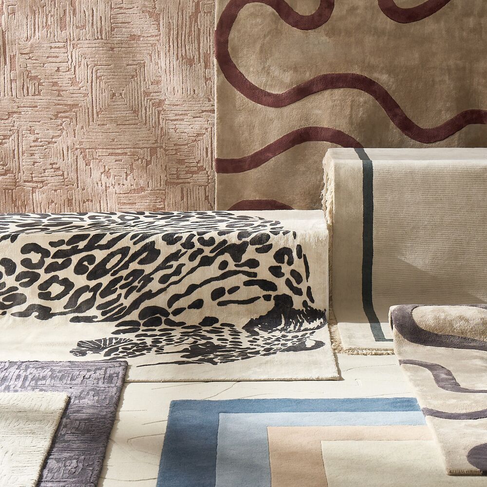 Layered luxury area rugs showcasing leopard print, wavy earth-toned runners, and bordered geometric neutral rugs.