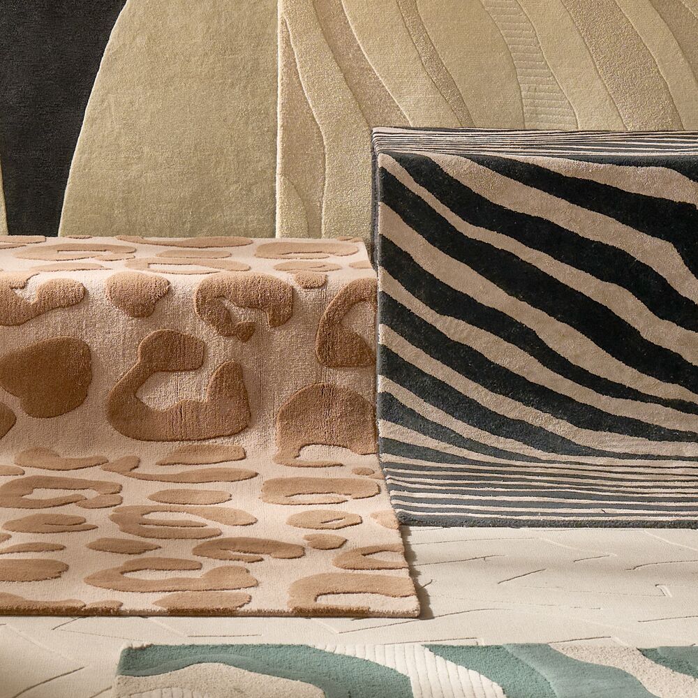 Modern area rugs displaying fluid organic wave patterns, featuring teal blue, cream, animal print, and beige textured wool fibers.