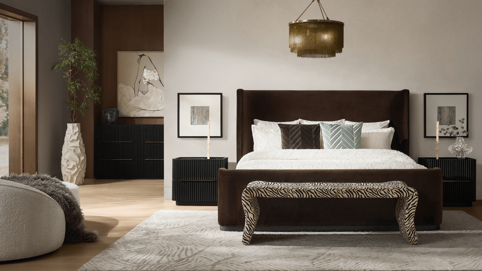 Luxurious bedroom featuring a dark brown tufted upholstered platform bed with crisp white bedding, accent pillows, matching nightstands with table lamps, and a warm amber glass chandelier.