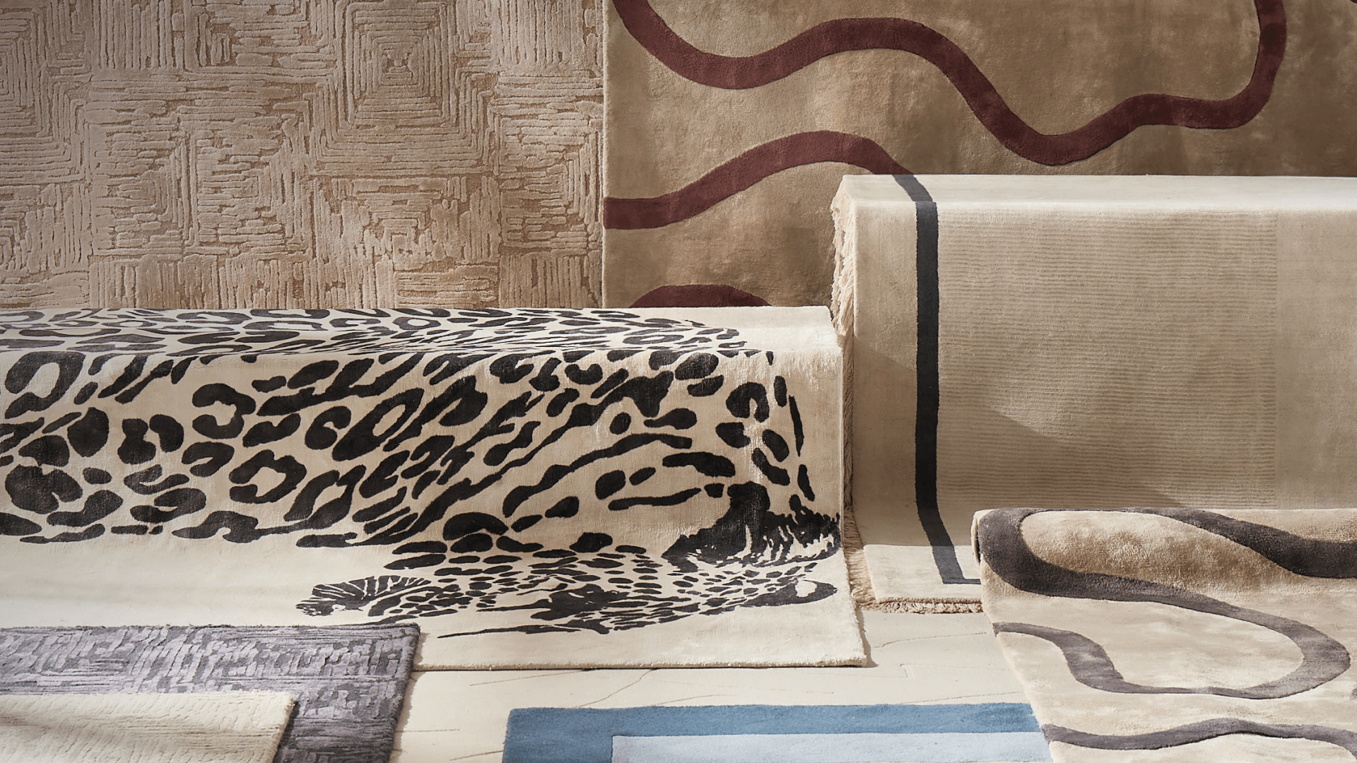 Curated gallery display of textured luxury area rugs featuring leopard print, wavy lines, and neutral woven patterns.