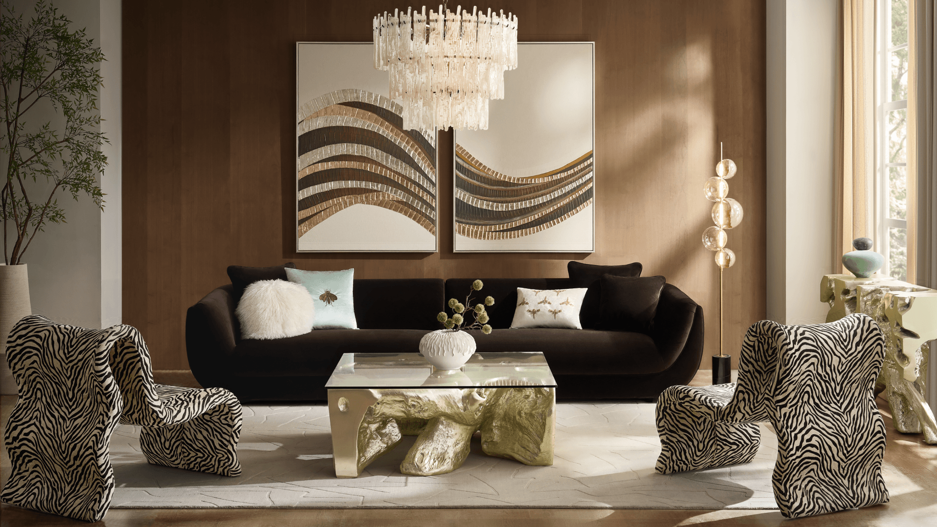 Dark brown velvet sofa styled with decorative accent pillows, paired with sculptural zebra print accent chairs, a gold glass-top coffee table, and large abstract wall art.