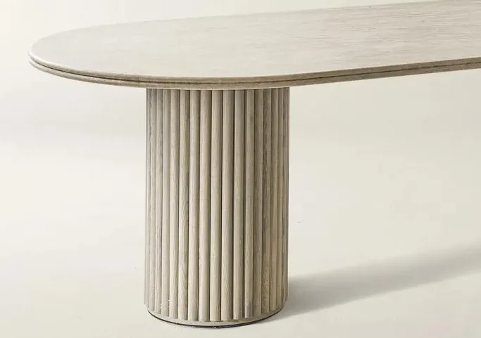 Double-layer travertine dining table with fluted wood base in a neutral living room