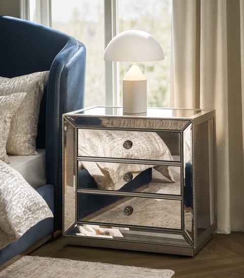 Mirrored furniture nightstand styled in a modern luxury bedroom.