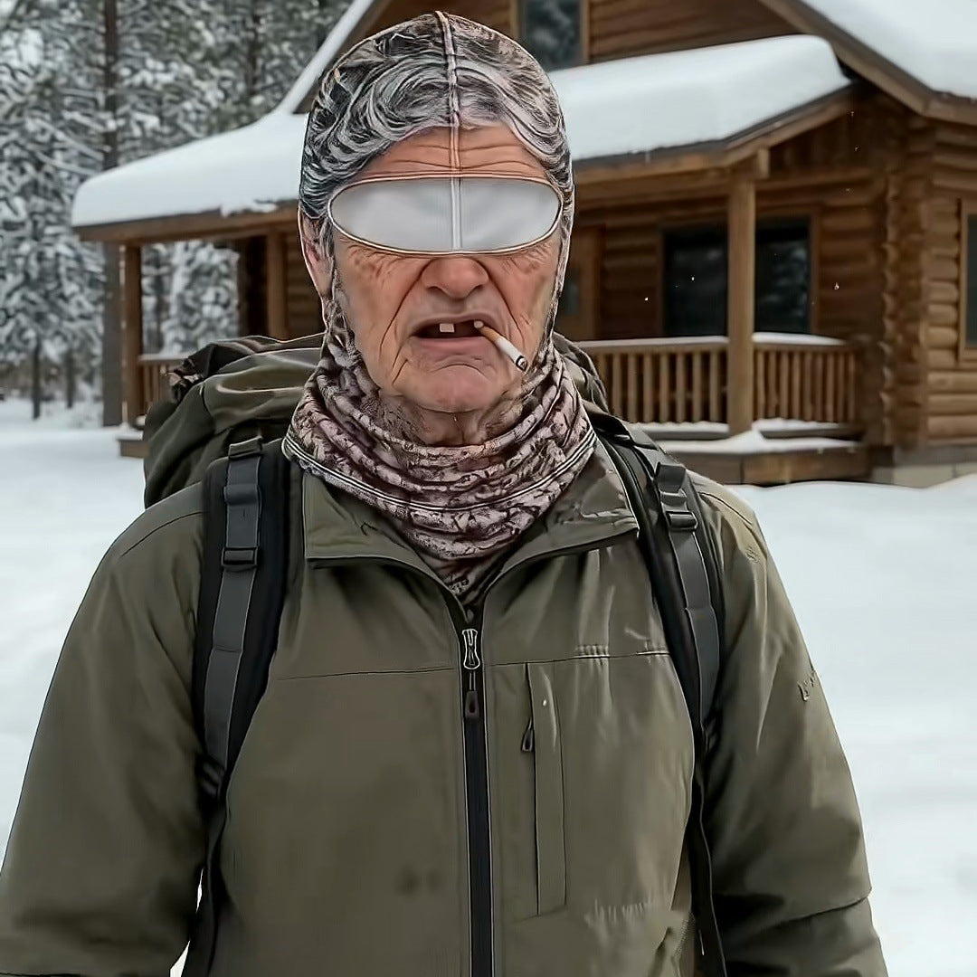 A man in an olive jacket and backpack wearing the Grandma mask in front of a snowy log cabin, no words