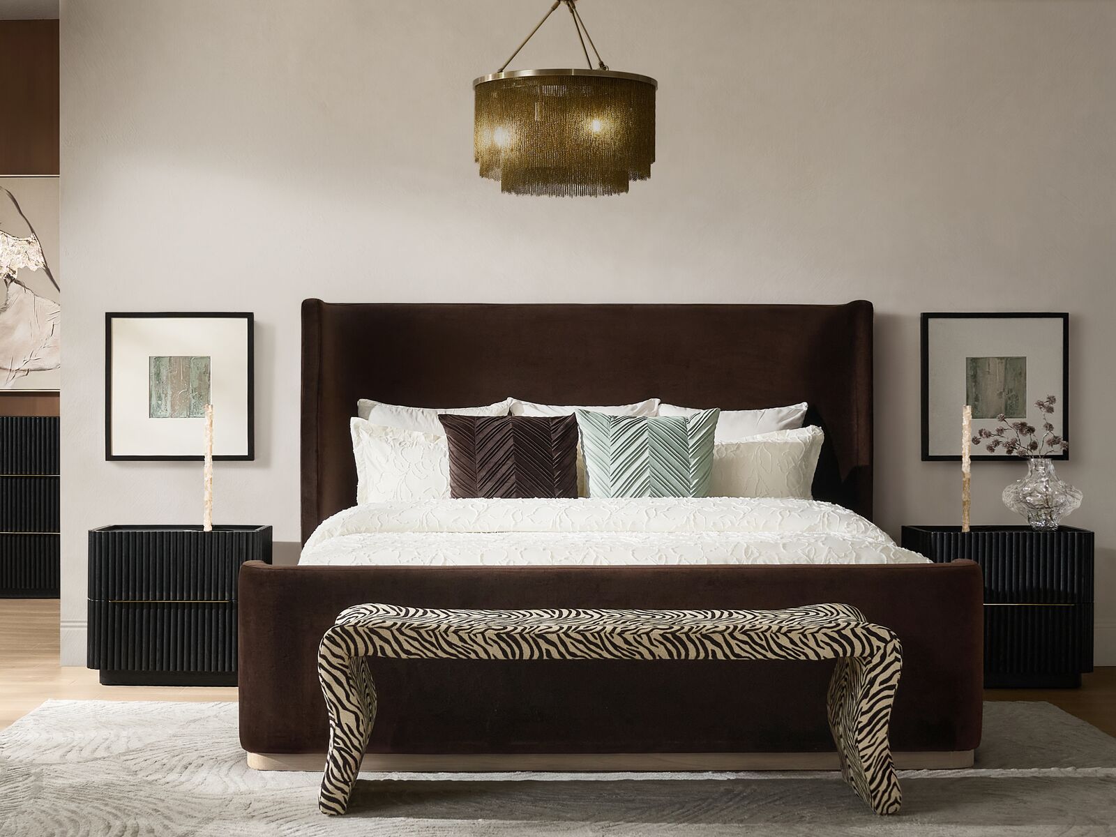 Modern luxury bedroom featuring a dark brown velvet wingback upholstered bed, curved zebra print bench, fluted black nightstands, and a tiered brass chain fringe chandelier.