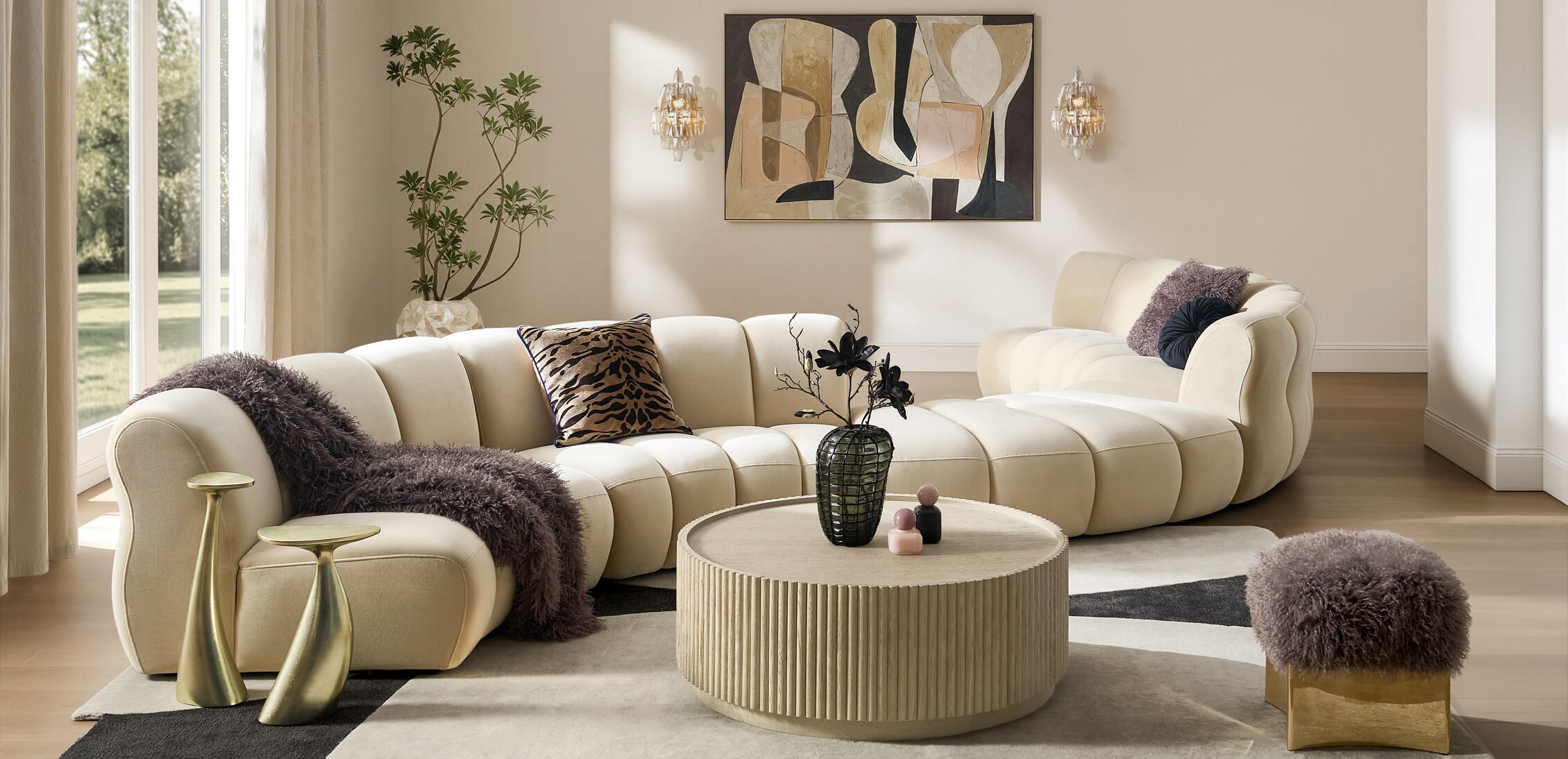 Cream modern channel-tufted curved sectional sofa paired with a fluted round coffee table and gold sculptural accents