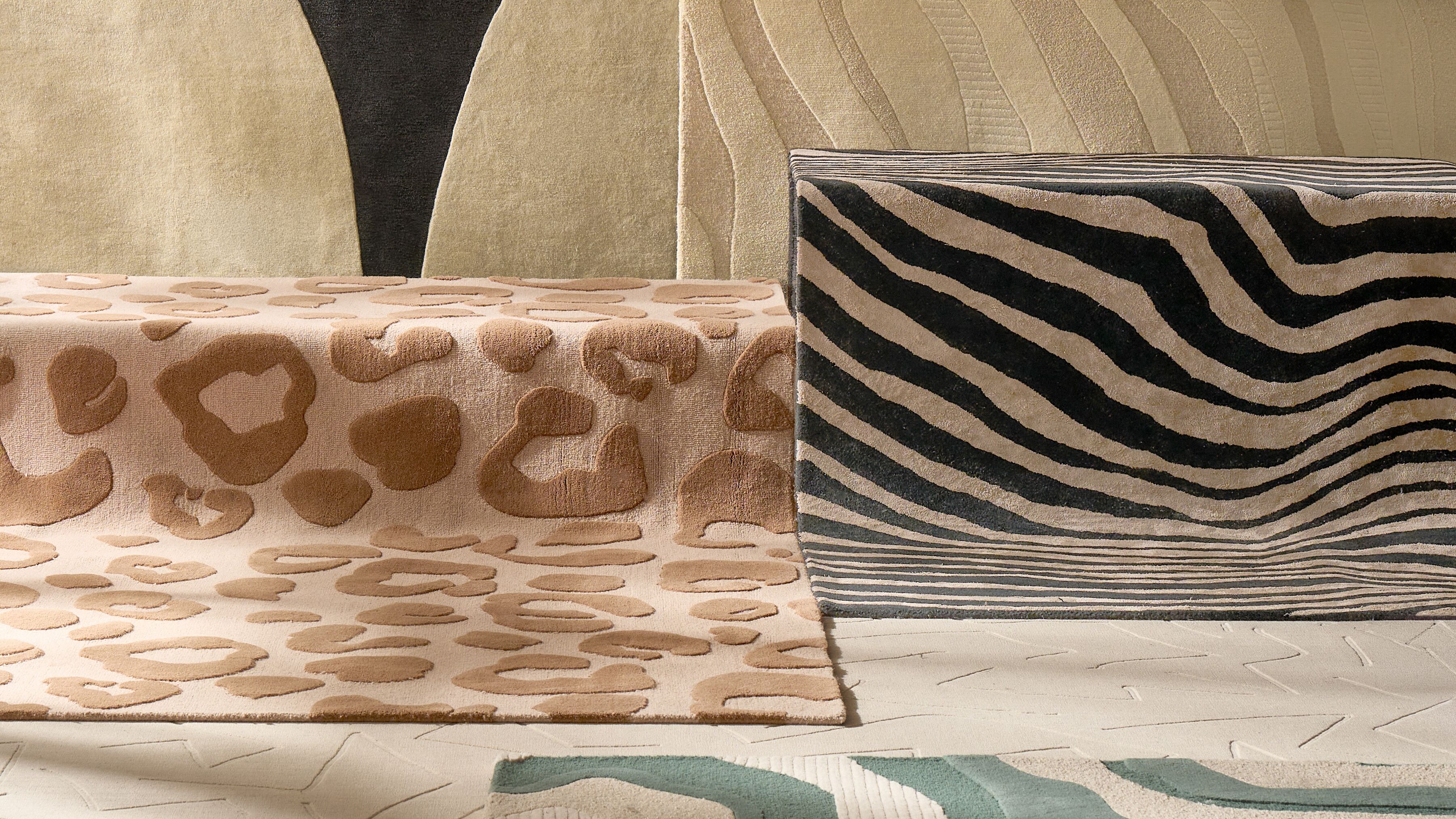 Close-up texture of layered luxury area rugs showing beige sculpted leopard animal spots and bold black and cream wavy zebra stripes.