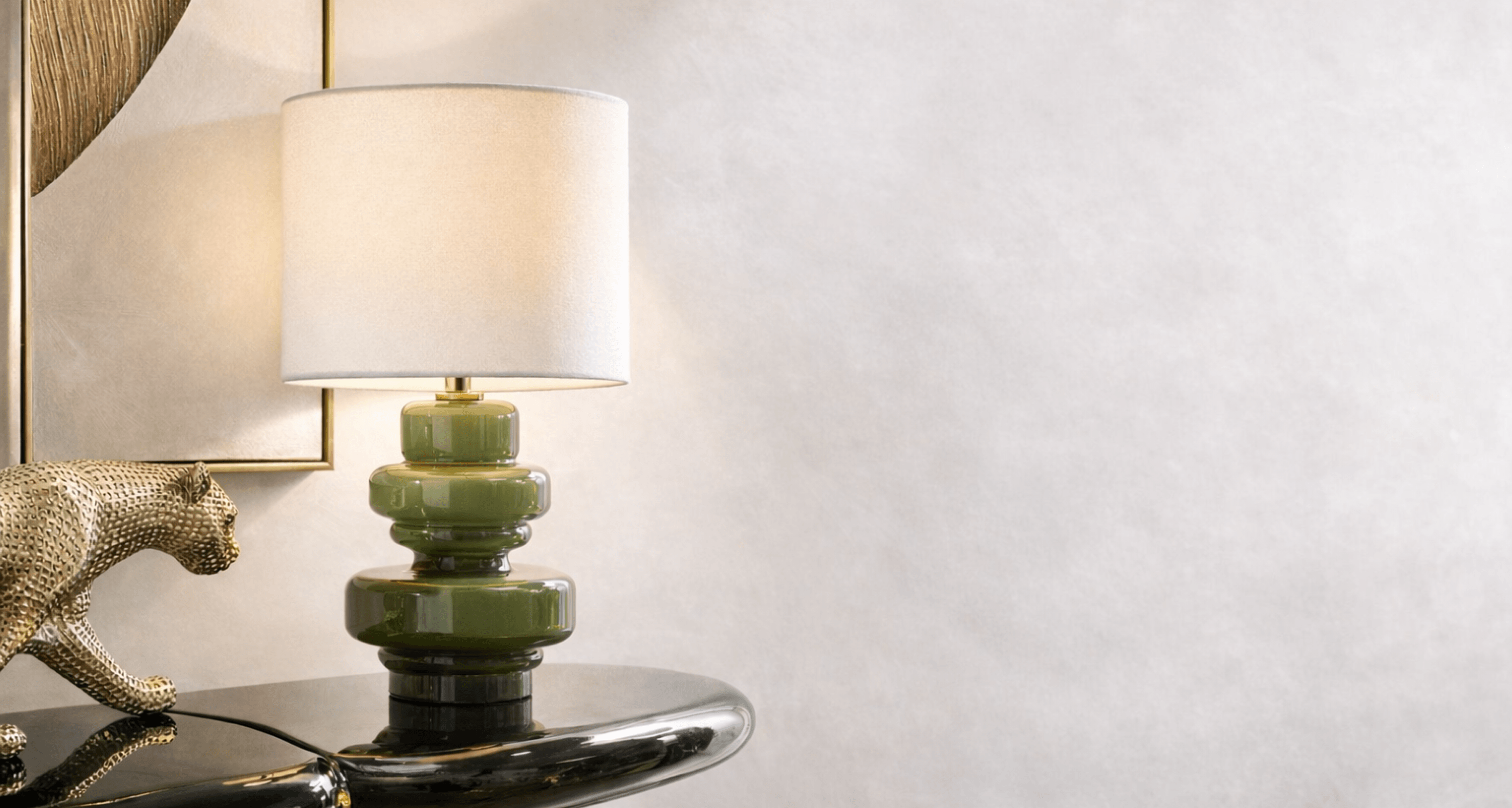 Modern olive green stacked ceramic table lamp with a crisp white drum shade styled on a high-gloss black console table.