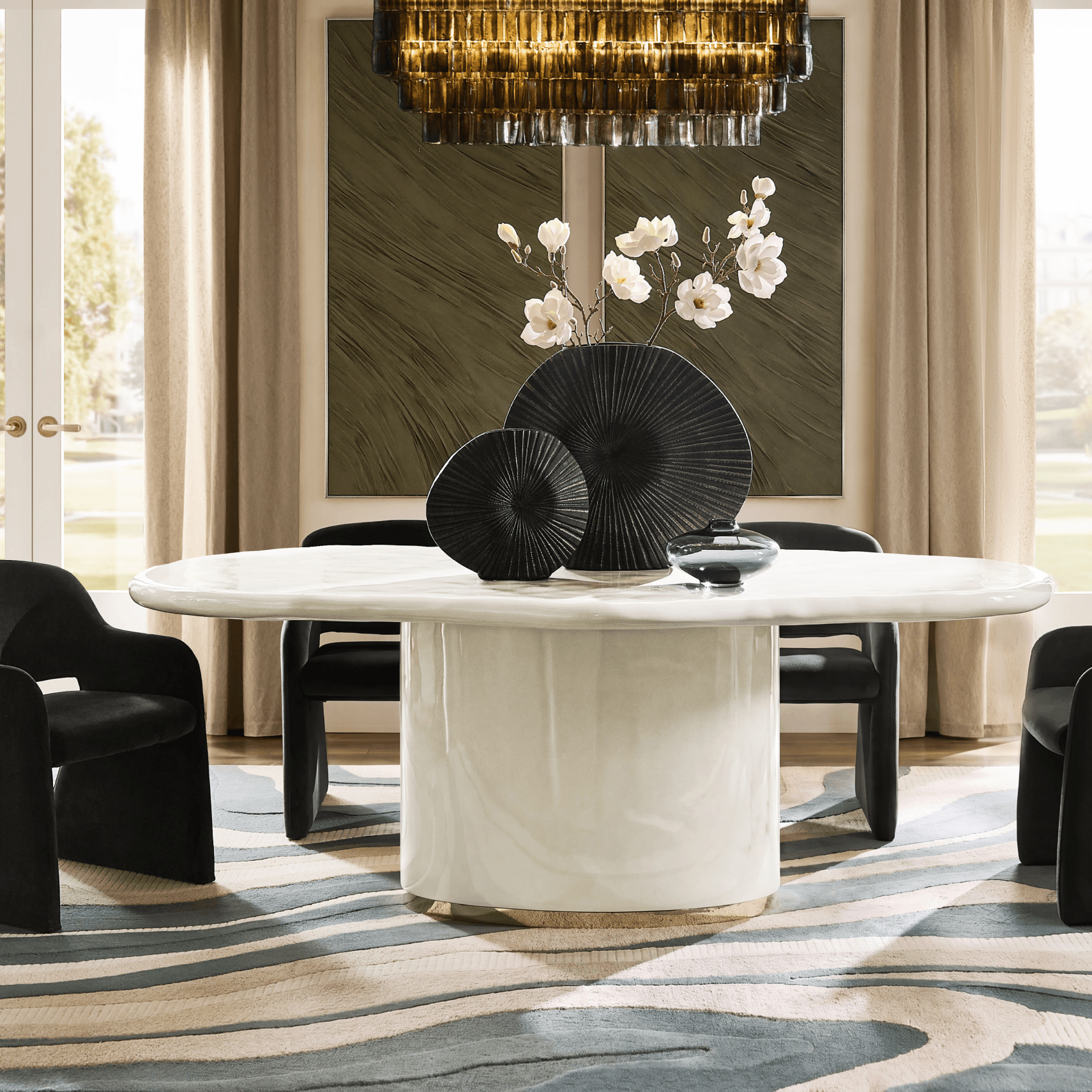 Modern white oval dining table styled with black ribbed decorative plates and white florals, set on a wavy patterned rug.