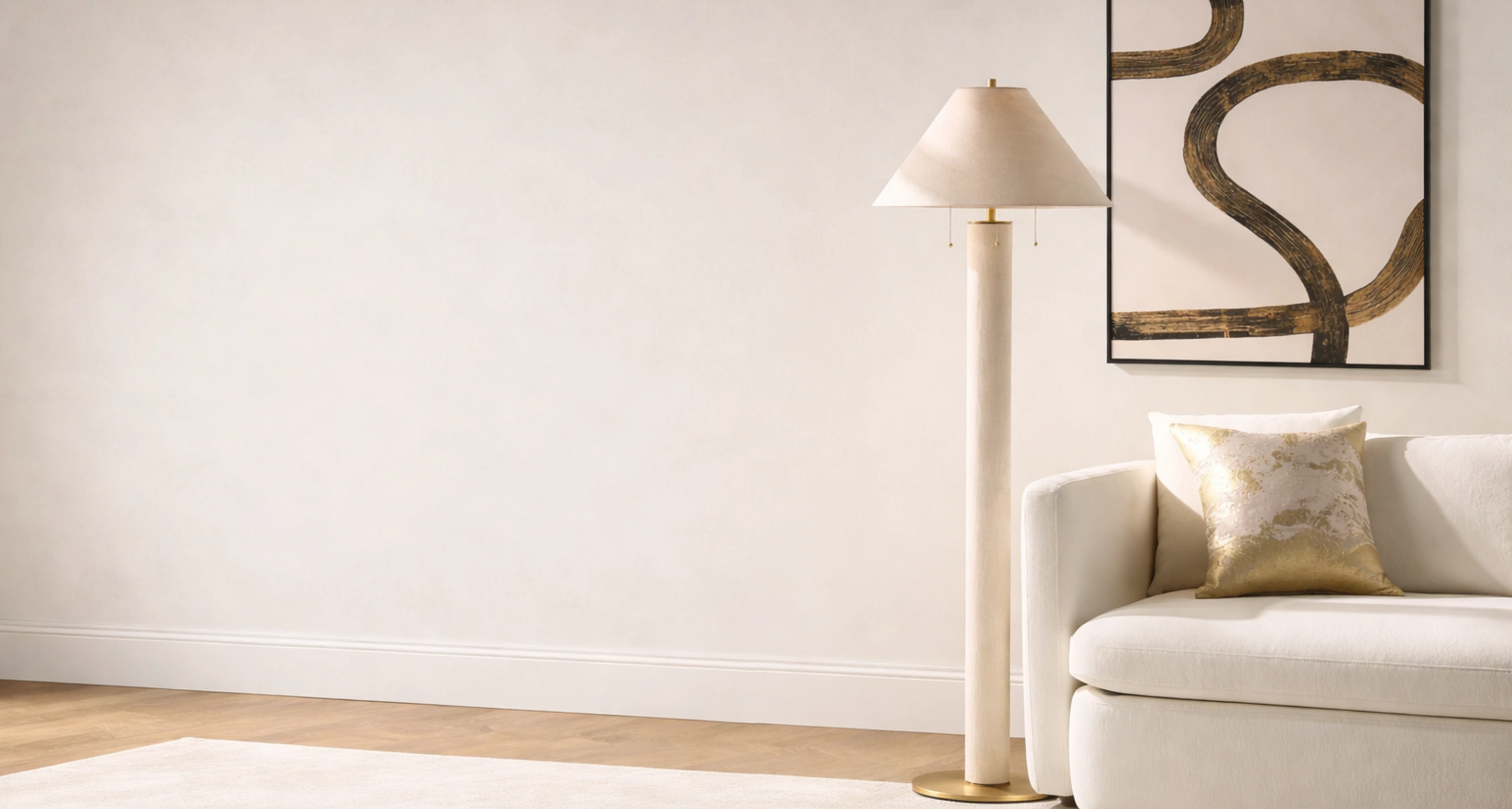 Modern cylindrical cream floor lamp with a classic conical shade placed beside a white upholstered sofa and abstract brushstroke wall art.