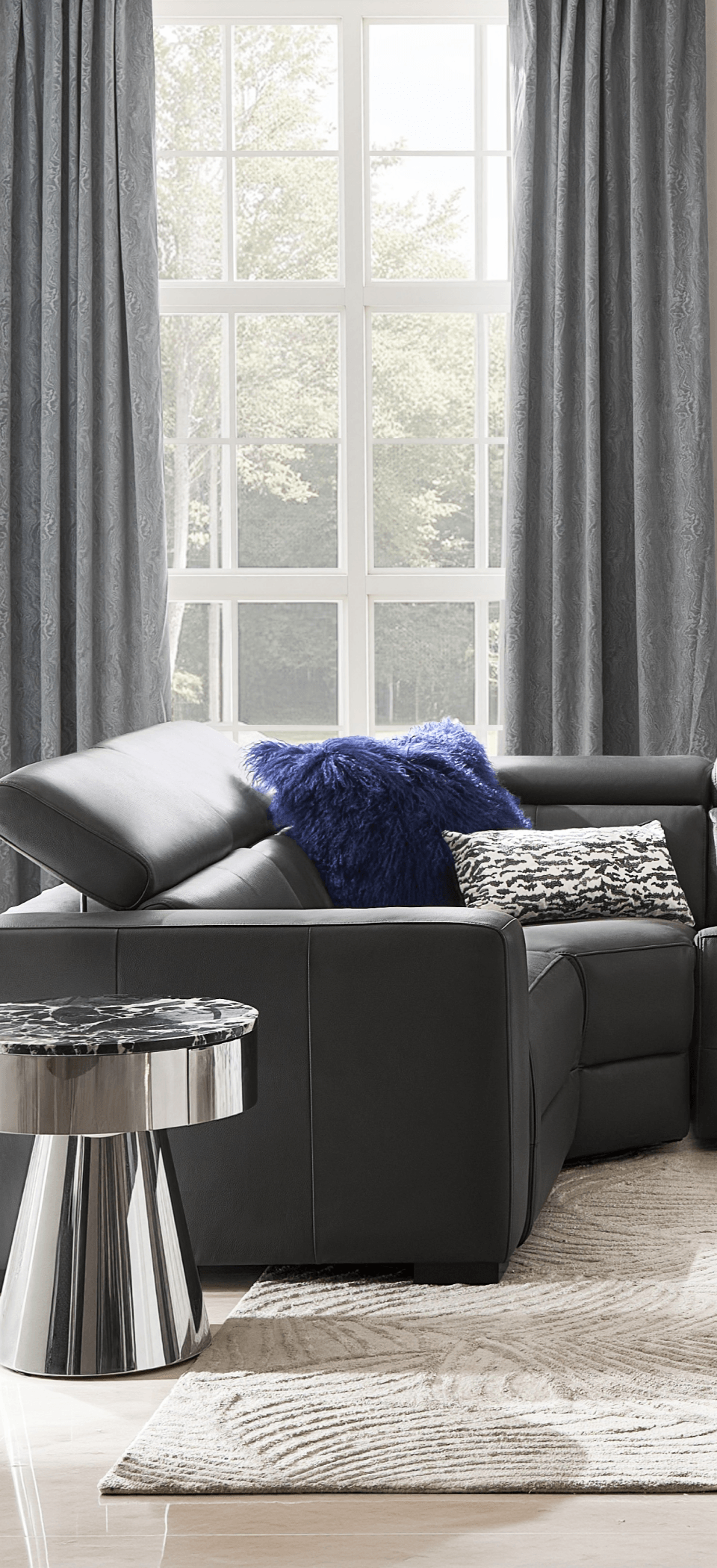 Sleek grey modern power motion recliner sectional sofa placed near a window with sheer curtains and polished accent table