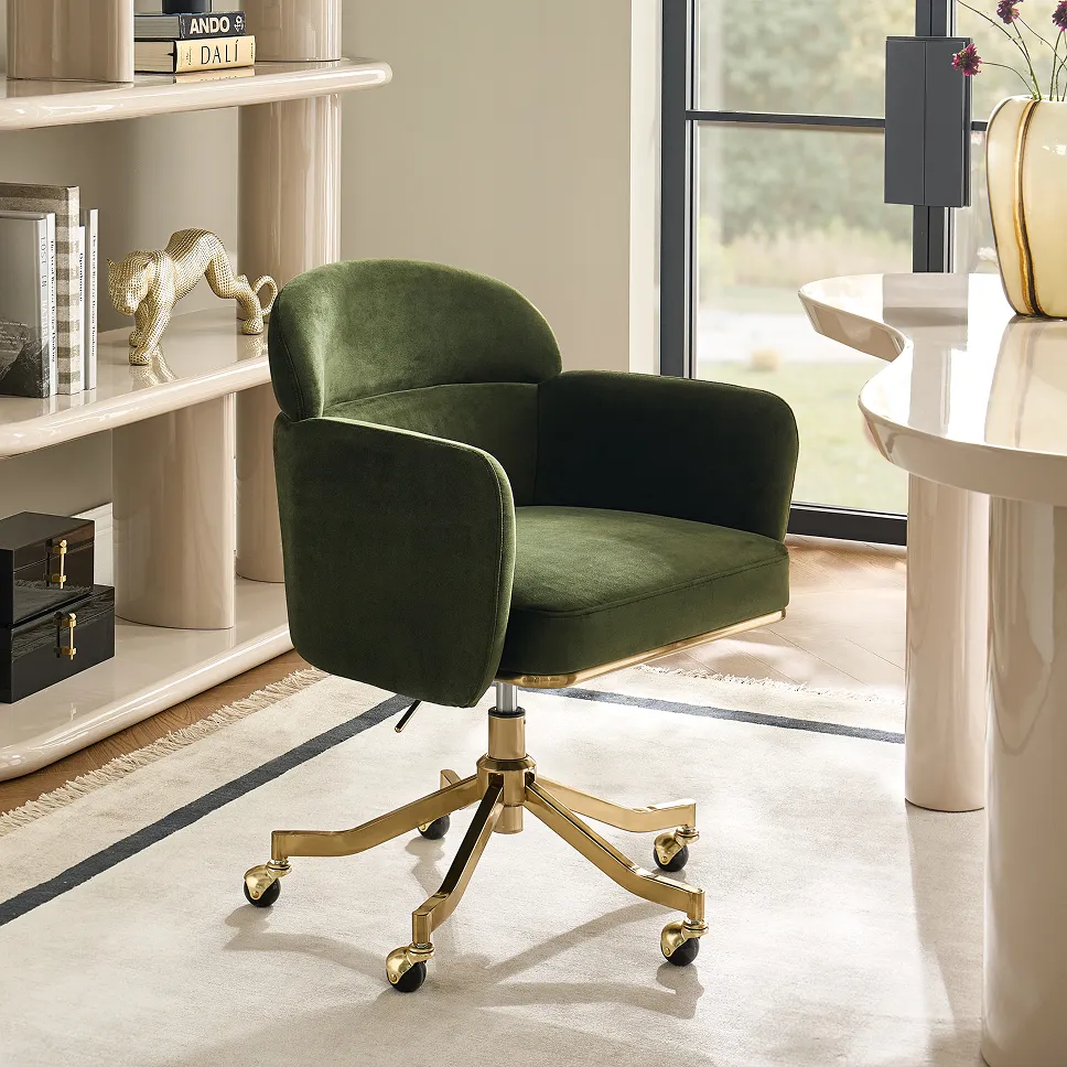 A modern olive green velvet executive desk chair with a gold brass 5-star swivel base with casters, set in a bright luxury home office beside a glossy cream desk.