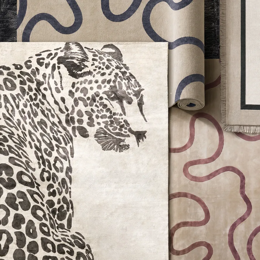 Overhead view of artisanal rugs featuring a bold leopard-patterned rug, squiggly organic line rugs in navy and burgundy, and a fringed bordered rug.