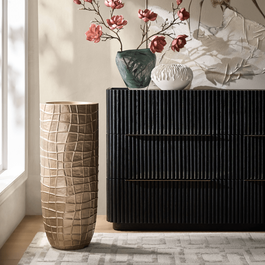 Fluted black dresser paired with a tall metallic textured vase and floral branch decor. 
