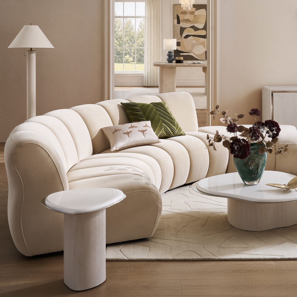 A natural curved sectional sofa paired with white lacquered finished coffee tables and a tall floor lamp in a modern living room setting.