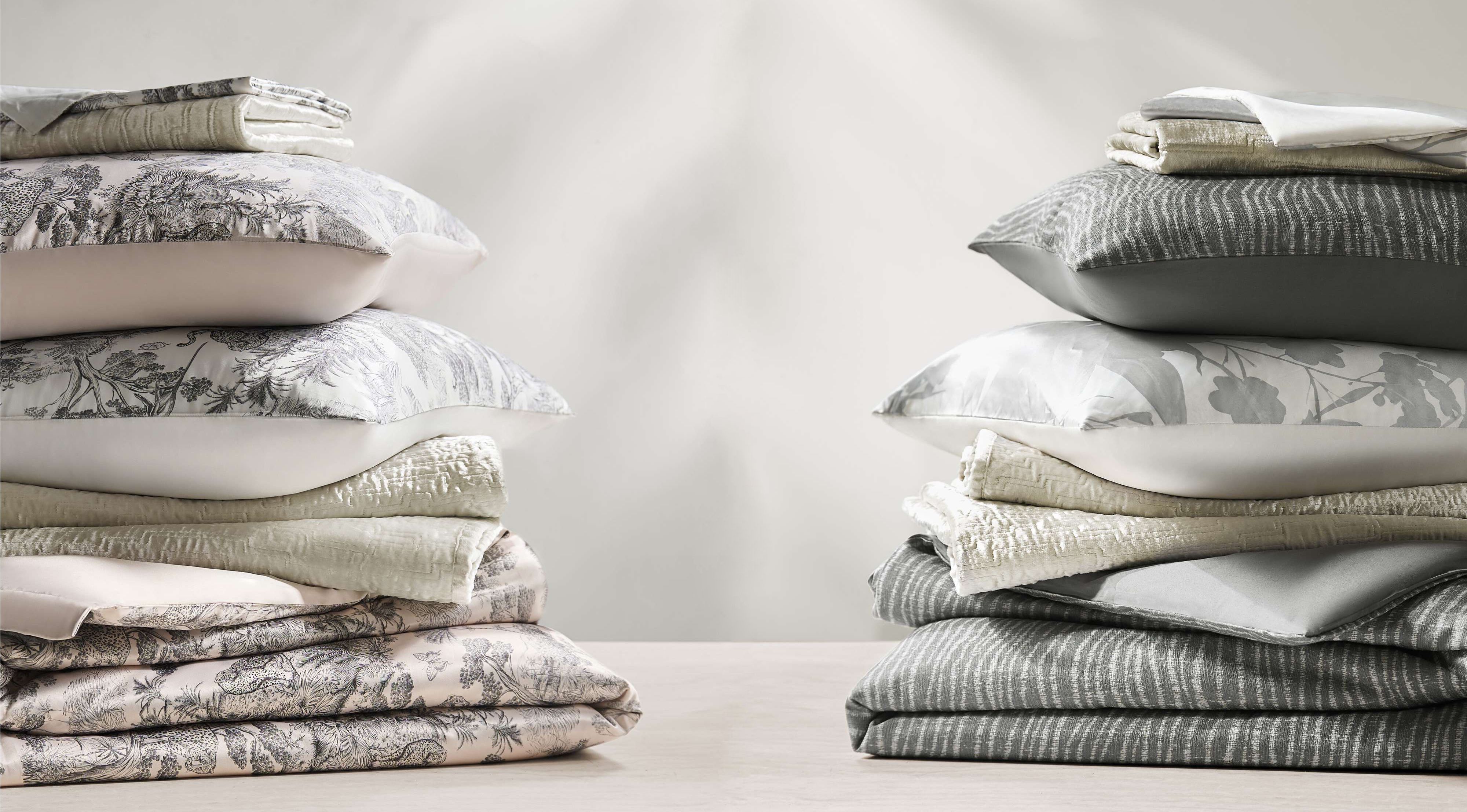 Stacks of neatly arranged bedding in soft colors and patterns.
