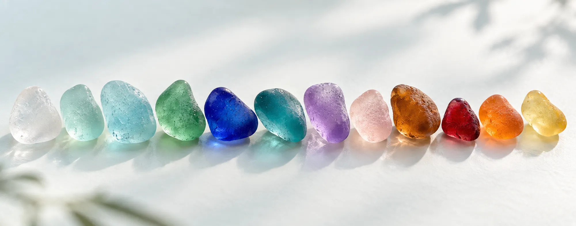 Sea glass pieces arranged by color from clear and green to blue purple and amber