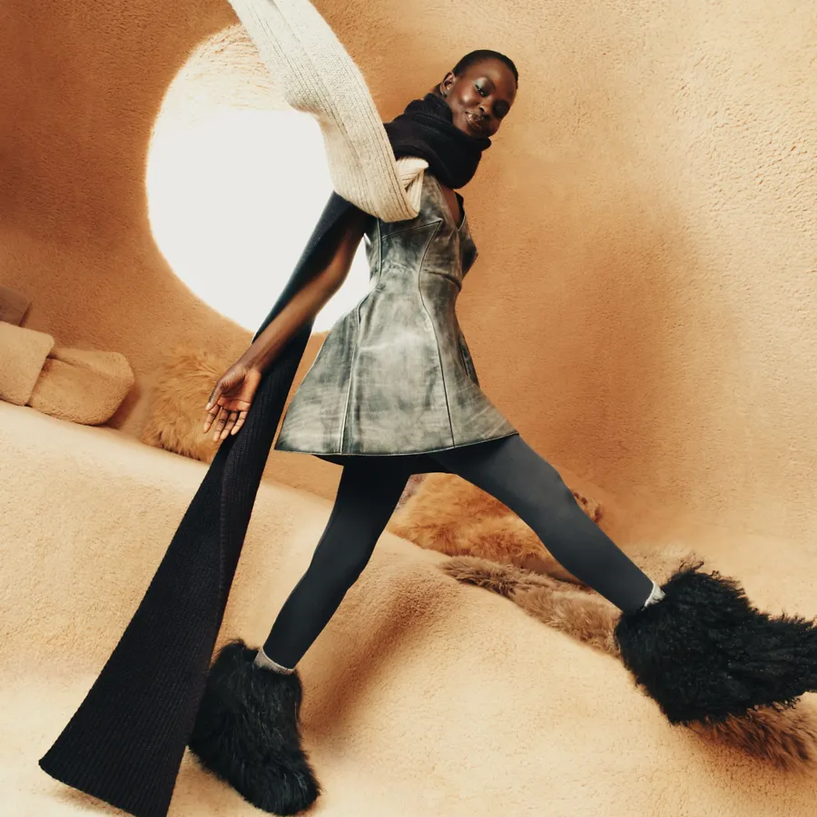 The UGG Classic Short Fluff Momma A feminine person wearing the UGG Classic Short Fluff Momma, paired with a playful fit and an oversized scarf.