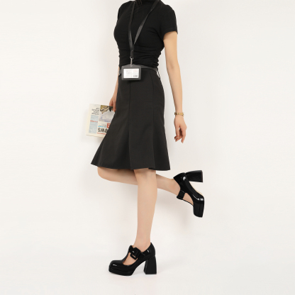 Close-up of model wearing black Mary Jane platform pumps with buckle strap and square toe