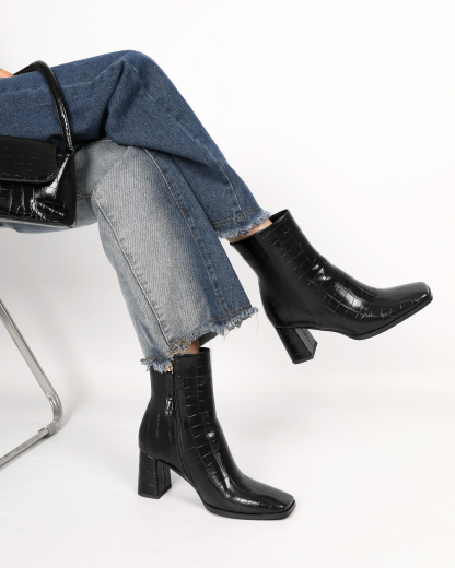 Model wearing black croc embossed ankle boots with jeans