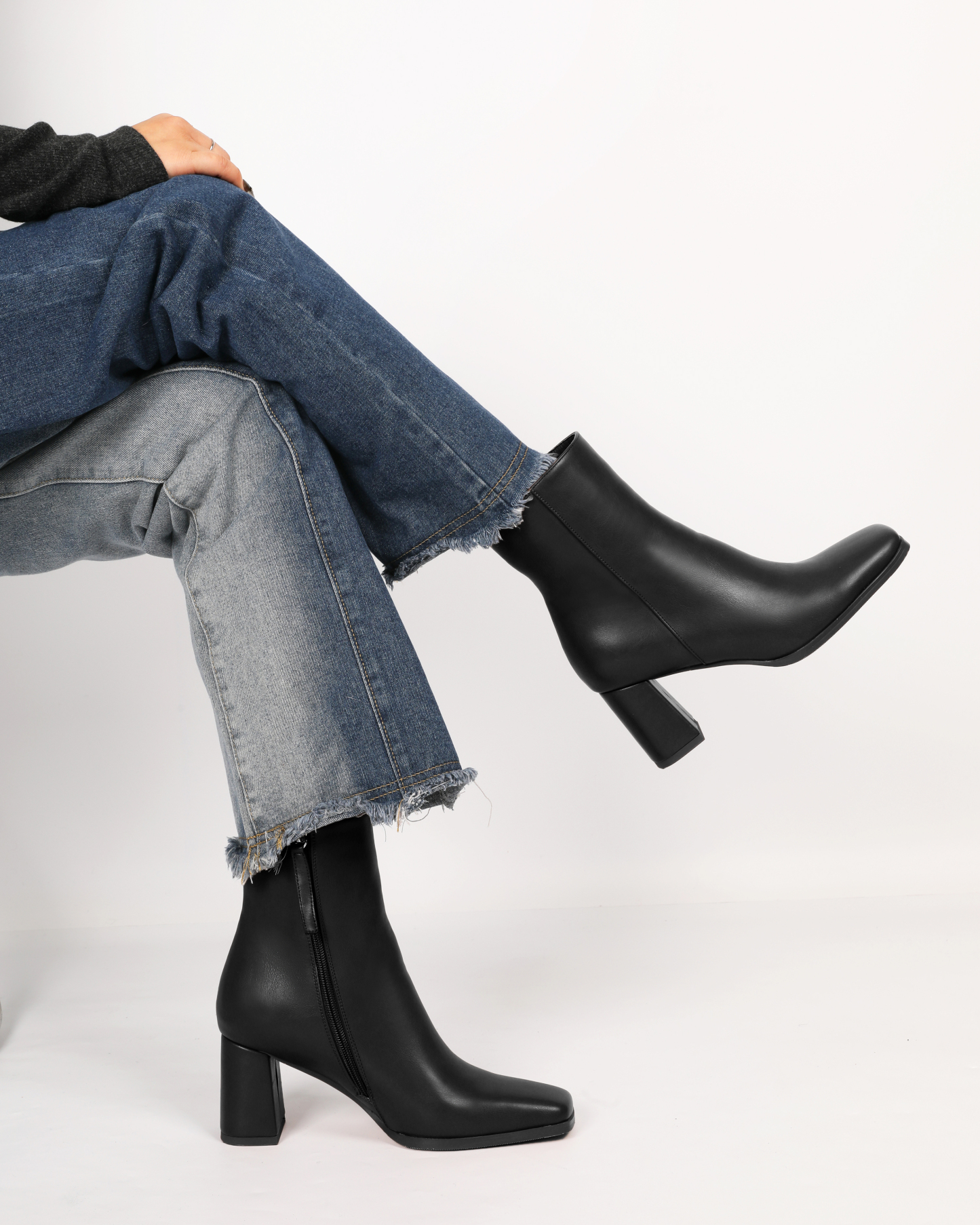 Model wearing black lambskin leather ankle boots with jeans