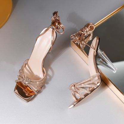 Gold rhinestone bow heels in angled studio lighting