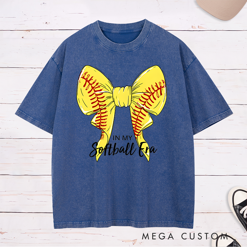 Personalized Softball Era Washed T-Shirt Design Showcasing a Vibrant Yellow Bow Inspired by Softball Stitching Paired with Customizable Text Perfect for Teams Players and Fans to Celebrate Their Love for the Game in Style