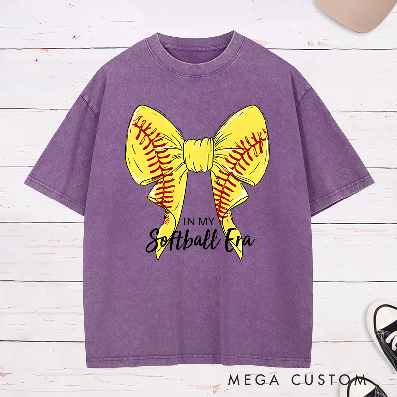 Personalized Softball Era Washed T-Shirt Design Showcasing a Vibrant Yellow Bow Inspired by Softball Stitching Paired with Customizable Text Perfect for Teams Players and Fans to Celebrate Their Love for the Game in Style