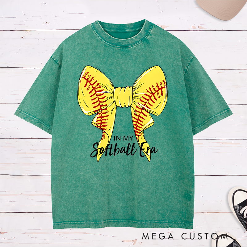 Personalized Softball Era Washed T-Shirt Design Showcasing a Vibrant Yellow Bow Inspired by Softball Stitching Paired with Customizable Text Perfect for Teams Players and Fans to Celebrate Their Love for the Game in Style