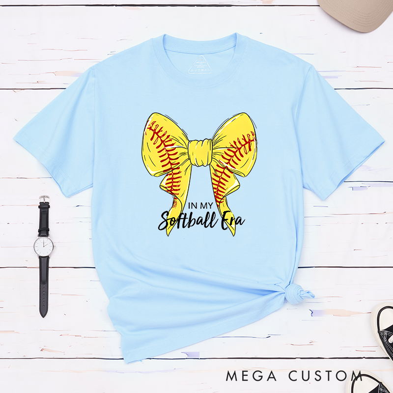 Personalized Softball Era T-Shirt Design Showcasing a Vibrant Yellow Bow Inspired by Softball Stitching Paired with Customizable Text Perfect for Teams Players and Fans to Celebrate Their Love for the Game in Style