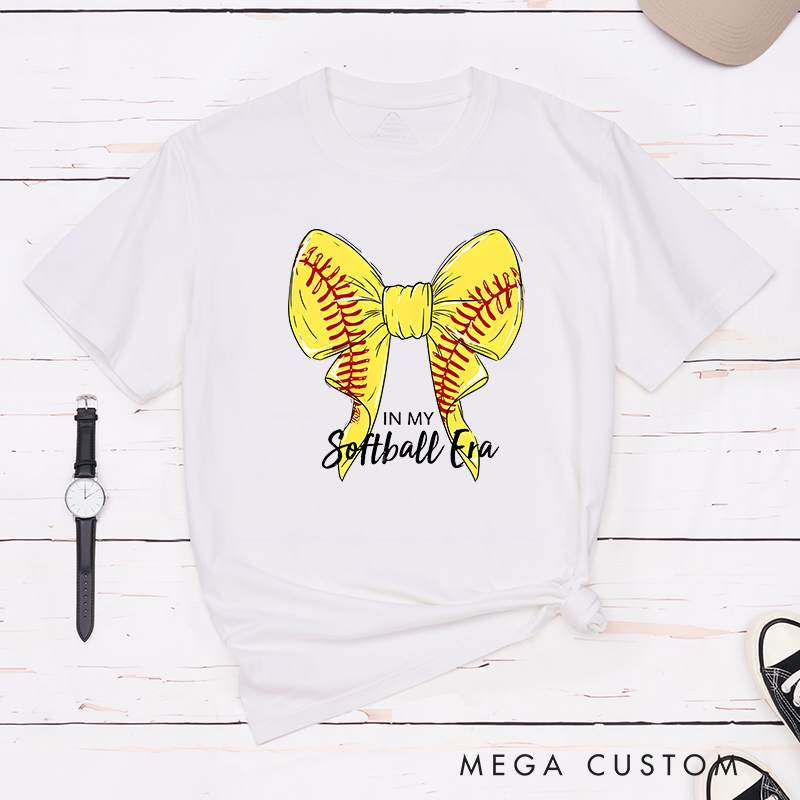 Personalized Softball Era T-Shirt Design Showcasing a Vibrant Yellow Bow Inspired by Softball Stitching Paired with Customizable Text Perfect for Teams Players and Fans to Celebrate Their Love for the Game in Style