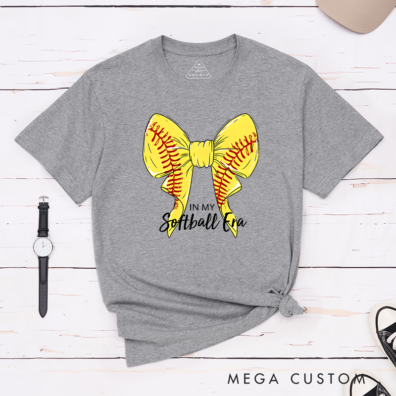 Personalized Softball Era T-Shirt Design Showcasing a Vibrant Yellow Bow Inspired by Softball Stitching Paired with Customizable Text Perfect for Teams Players and Fans to Celebrate Their Love for the Game in Style
