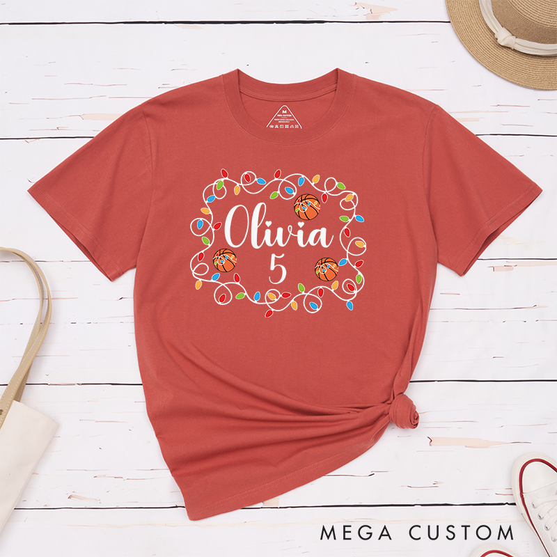Personalized Christmas T-Shirt with Custom Name, Number, Basketballs, and Festive String Lights Design
