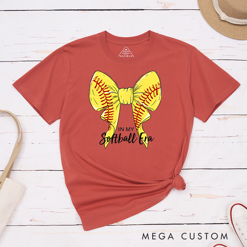 Personalized Softball Era T-Shirt Design Showcasing a Vibrant Yellow Bow Inspired by Softball Stitching Paired with Customizable Text Perfect for Teams Players and Fans to Celebrate Their Love for the Game in Style