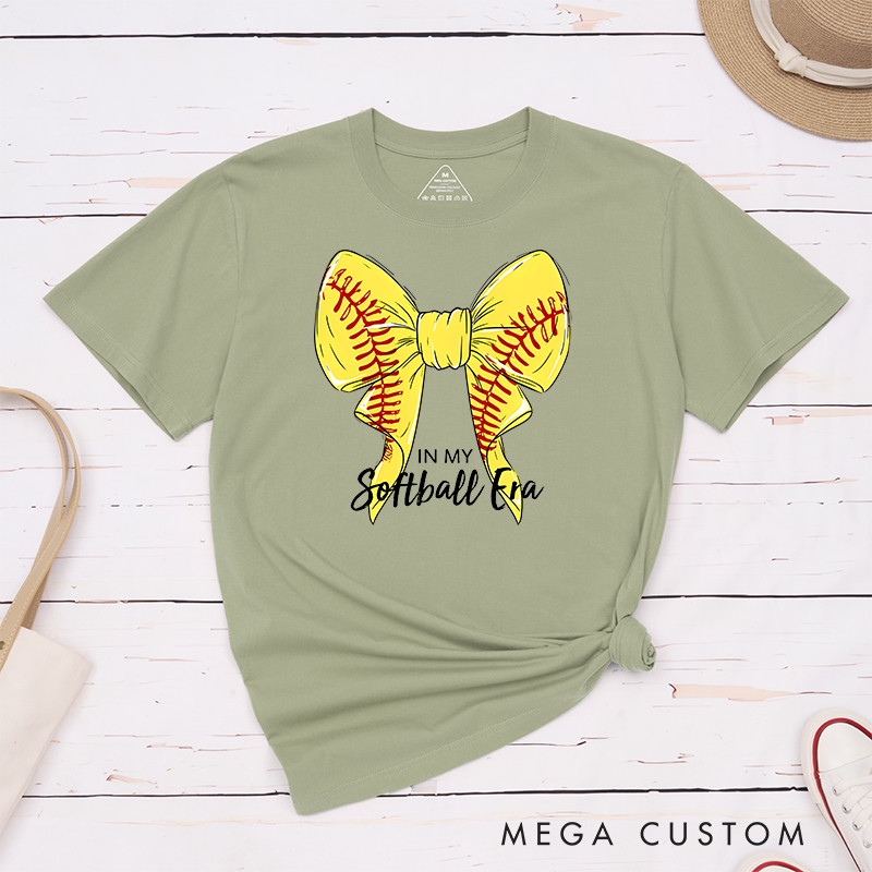 Personalized Softball Era T-Shirt Design Showcasing a Vibrant Yellow Bow Inspired by Softball Stitching Paired with Customizable Text Perfect for Teams Players and Fans to Celebrate Their Love for the Game in Style
