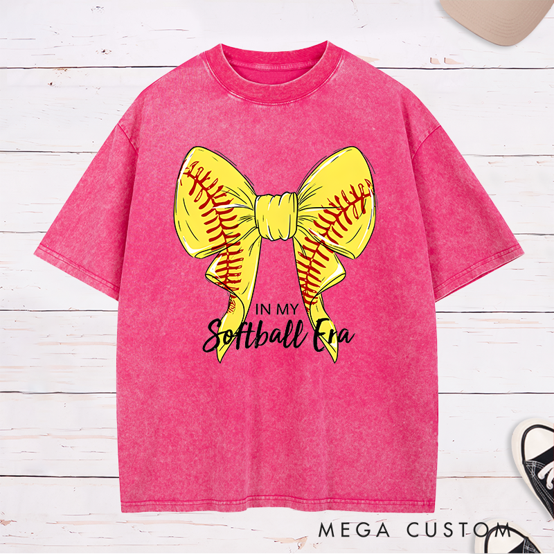 Personalized Softball Era Washed T-Shirt Design Showcasing a Vibrant Yellow Bow Inspired by Softball Stitching Paired with Customizable Text Perfect for Teams Players and Fans to Celebrate Their Love for the Game in Style