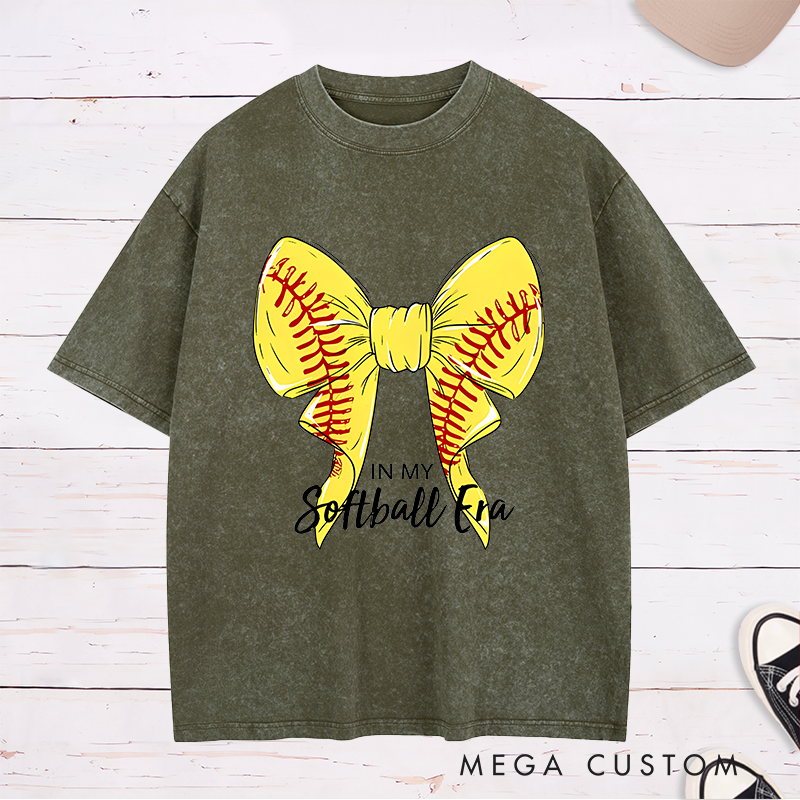 Personalized Softball Era Washed T-Shirt Design Showcasing a Vibrant Yellow Bow Inspired by Softball Stitching Paired with Customizable Text Perfect for Teams Players and Fans to Celebrate Their Love for the Game in Style