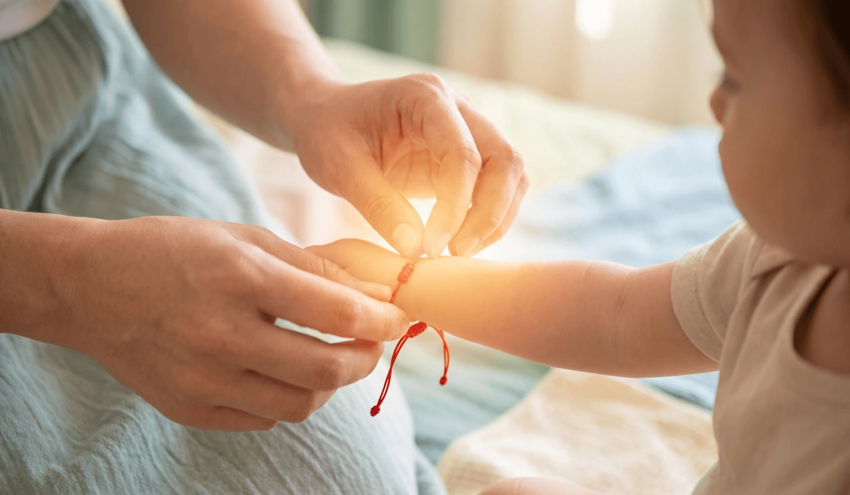 A parent placing a protection bracelet on a child's left wrist to set a spiritual intention for safety.